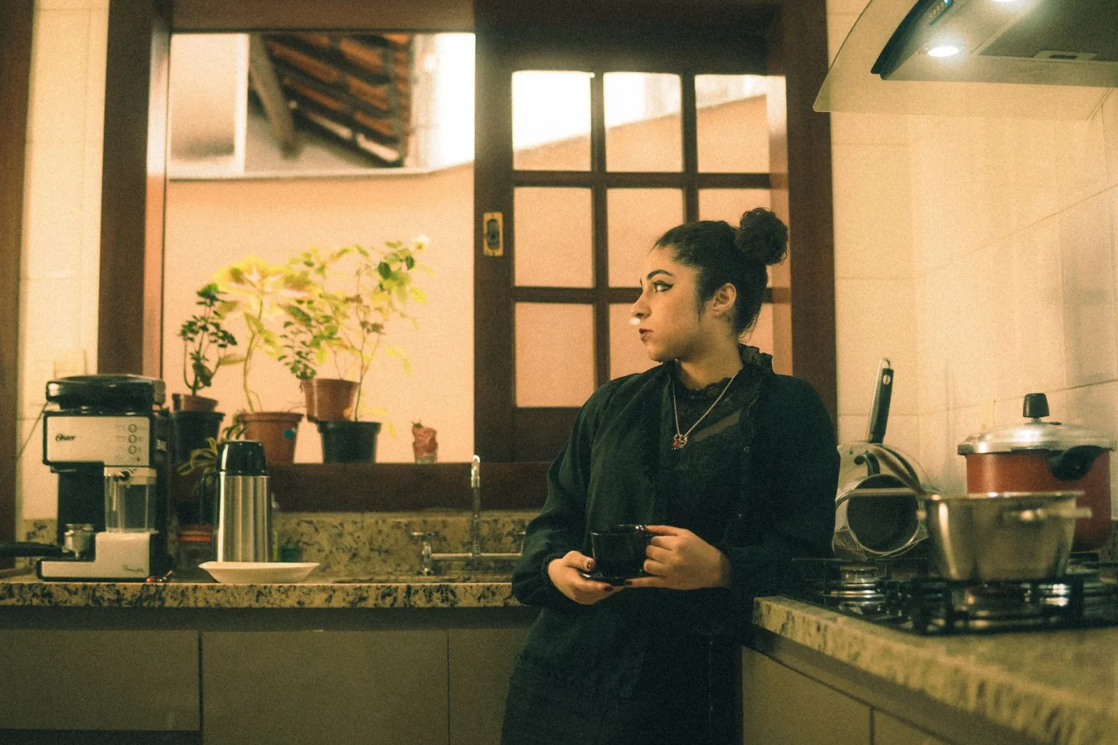 A woman standing in a warm kitchen holding a mug of coffee, representing the quiet after food noise fades.